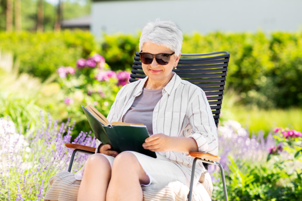 senior women reading a book outside in the summer
