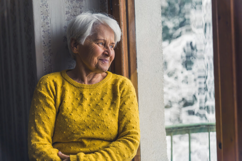 Elderly women looking out a window - winter wellness tips