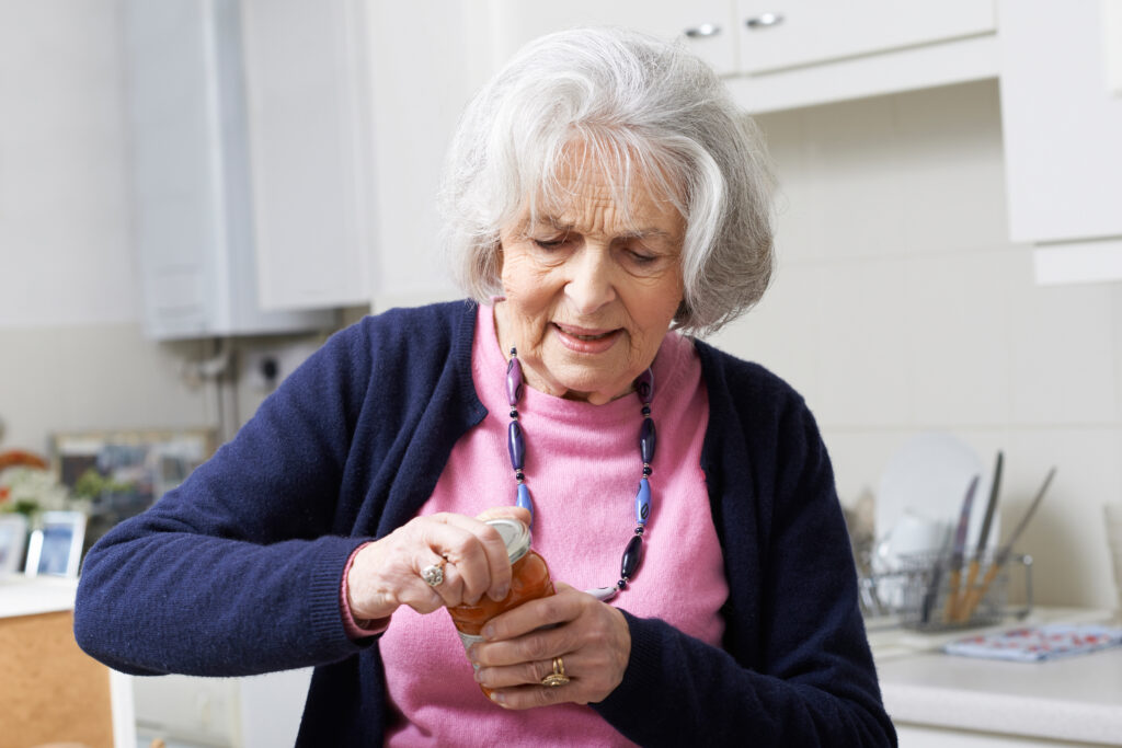 Senior woman struggling to open jar at home