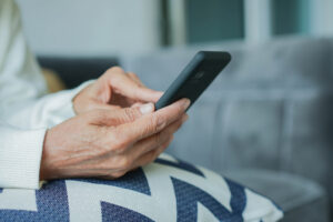 Close-up of an older adult's hands using a smartphone, a simple way to help keep an aging parent engaged from a distance